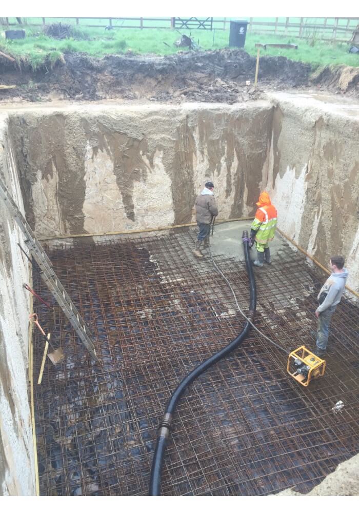 Concrete vibration & Ronimix operatives delivering concrete from our concrete pump to form a new basement floor
