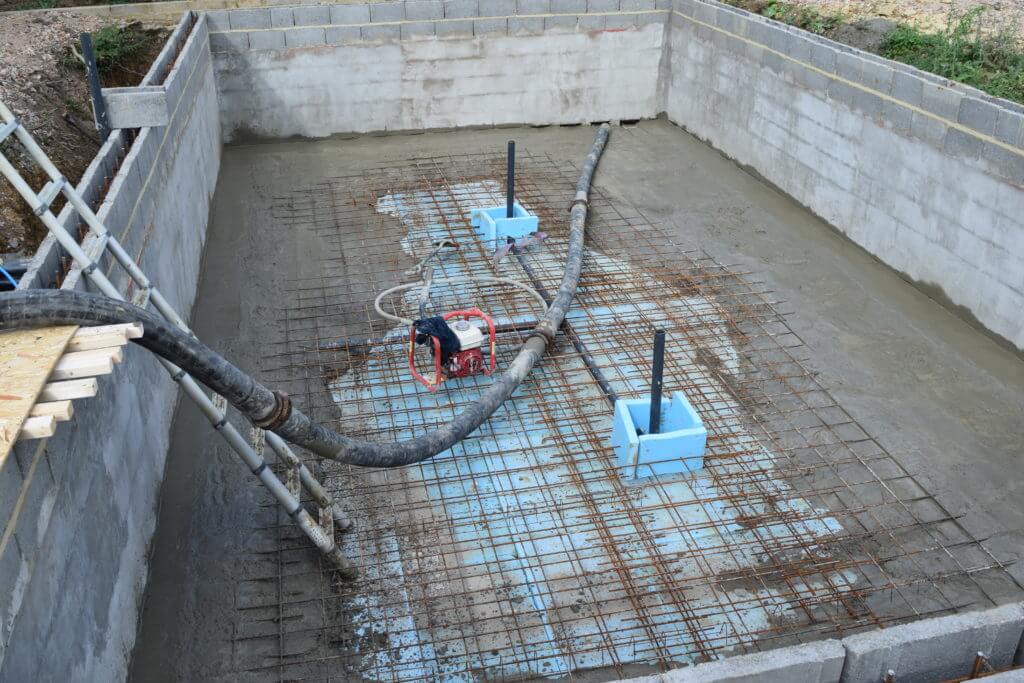 Partially completed swimming pool slab with concrete being pumped by Ronimix